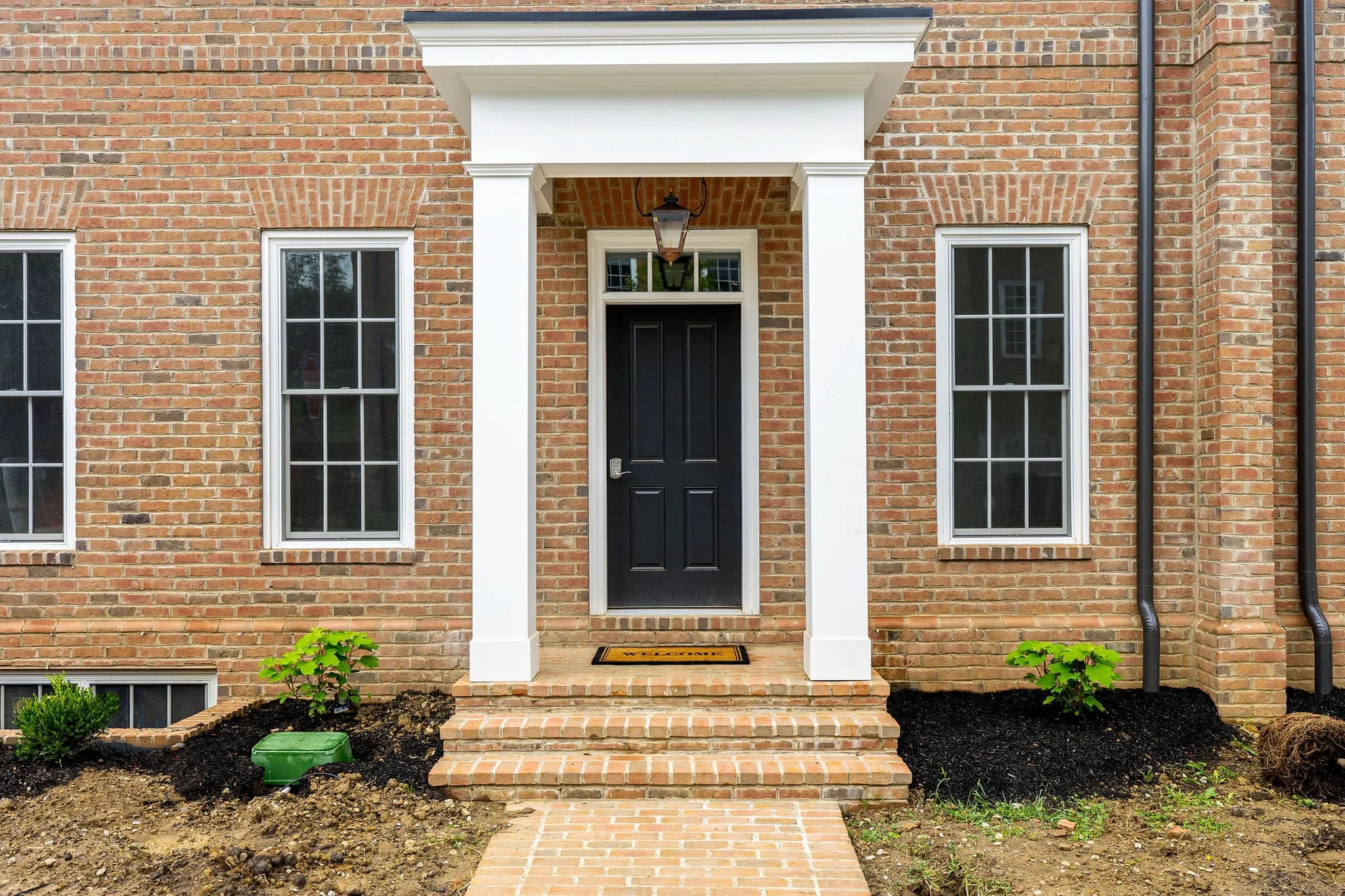 Front portico of 115 Keswick — brick, white columns, paneled door